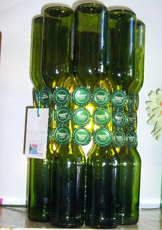 A shade of bottles that fits over a pillar candle or you can fit it over an old lamp. Great for those lazy summer evening braais on the patio! Stunning as a bar lamp. Decorations vary.